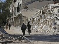 People walk past destroyed buildings in the Palestinian camp of Yarmuk southern Damascus on November 1, 2018. 
LOUAI BESHARA / AFP