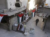 A man walks past destroyed buildings decorated with Palestinian flags in the Palestinian camp of Yarmuk southern Damascus on November 1, 2018. 
LOUAI BESHARA / AFP