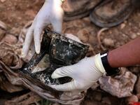 a member of the Yazidi minority searches in a wallet for clues, that might lead him to missing relatives in the remains of people killed by the Islamic State. (Safin HAMED / AFP)