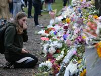 People pay their respects in front of floral tributes for victims of the March 15 mosque attacks, in Christchurch 
DAVID MOIR / AFP