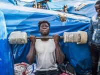 A sub-Saharan migrant lifts weights with a make-shift barbell between make-shift tents in the Oulad Ziane migrant camp in Casablanca on March 27, 2019. 
FADEL SENNA / AFP