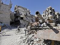 Boys ride their bicycle past a destroyed tank and buildings in the Palestinian camp of Yarmuk southern Damascus on November 1, 2018. 
LOUAI BESHARA / AFP