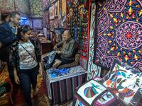 Customers walk in the shop of an Egyptian craftsman as he weaves a tapestry in his shop in Khayamiya Street, or the Street of Tent-makers, in the old city of the Egyptian capital Cairo on December 18, 2018. 
Mohamed el-Shahed / AFP
