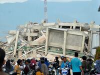 Residents gather to look at a collapsed building after an earthquake and tsunami hit Palu on Sulawesi island on September 29, 2018. (MUHAMMAD RIFKI / AFP)