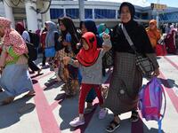 People gather on the apron as they wait to be evacuated by military aircraft at the quake-damaged Mutiara Sis Al Jufri airport in Palu, Indonesia's Central Sulawesi on September 30, 2018. (ADEK BERRY / AFP)