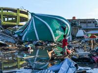 An earthquake victim salvages useable items near a collapsed mosque in Palu, Indonesia's Central Sulawesi on October 1, 2018. (JEWEL SAMAD / AFP)