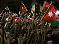 Protesters raise their hands and wave flags near members of the gendarmerie and security forces during a demonstration outside the prime minister's office in the capital Amman late on June 3, 2018. 
Khalil MAZRAAWI / AFP