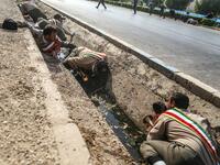 This picture taken on September 22, 2018 in the southwestern Iranian city of Ahvaz shows Iranian soldiers taking cover in a rain gutter off a street at the scene of an attack on a military parade that was marking the anniversary of the outbreak of its devastating 1980-1988 war with Saddam Hussein's Iraq.(MORTEZA JABERIAN / ISNA / AFP)