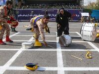 September 22, 2018 in the southwestern Iranian city of Ahvaz shows members of an Iranian military marching band reaching for their fallen instruments at the scene of an attack on a military parade that was marking the anniversary of the outbreak of its devastating 1980-1988 war with Iraq. (MORTEZA JABERIAN / ISNA / AFP)