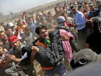 Palestinians carry a demonstrator injured during clashes with Israeli forces near the border between the Gaza strip and Israel east of Gaza City on May 14, 2018. Thomas COEX / AFP