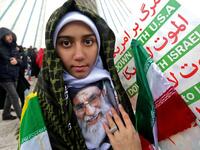 An Iranian girl poses with a potrait of the country's Supreme Leader Ali Khamenei with signs reading "Down with USA" and "Down with Israel" during a ceremony celebrating the 40th anniversary of Islamic Revolution.
ATTA KENARE / AFP