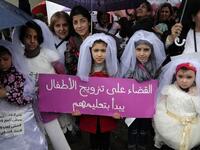 Young Lebanese girls disguised as brides hold a placard as they participate in a march against marriage before the age of 18, in the capital Beirut on March 2, 2019. The placard in Arabic reads "The end of child marriage begins by educating them". 
ANWAR AMRO / AFP