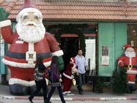Palestinian women walk past a giant Santa Claus in the biblical West Bank town of Bethlehem, as the town prepares for scores of Christian pilgrims gathering in the traditional birthplace of Jesus Christ to celebrate Christmas.