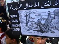 No for killing innocent children sign, held by Palestinian children who took a part in protesting against the invasion of Gaza two years ago.