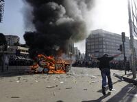 Supporters of the Future Movement gather as they watch the torched vehicle belonging to the Arabic language al-Jazeera satellite television station.