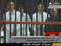 Egyptian former interior minister Habib al-Adly (R) stands along side Alaa (2nd R) and Gamal (L) Mubarak in a cage-like holding cell in the court room in the police academy.