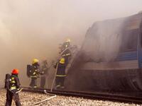 Israeli fire fighters spray water to extinguish the flames of a burning train coach near Kibbutz Shfaim, close to the Israeli city of Netanya about 15 kms north of Tel Aviv, after the passenger train cought fire, injuring almost 50 people, in an apparent accident.