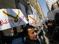 Egyptian riot policemen stop protesters from approaching the parliament building in downtown Cairo during a demonstration. Arabic writing on placards reads "No for economic suicide".