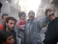 اب سوري يحمل طفلته بعد نجاتهم من قصف بالبراميل المتفجرة من قبل الطيران النظامي في حلب/أ.ف.ب