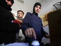 A woman dips her index finger in ink after casting her ballot for Syria's first local elections since 2011, on September 16, 2018. (LOUAI BESHARA / AFP)