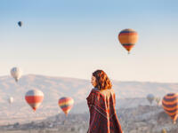A tourist on a mountain top enjoying wonderful view of the sunrise and balloons in Cappadocia (Shutterstock/File Photo)