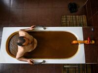 A man bathes in a tub filled with Naftalan crude oil during a treatment session at Sehirli Naftalan Health Center, some 300 kilometres (186 miles) from capital Baku, on March 21, 2019. Immersed up to her neck in crude oil, a Russian woman suffering from joint disease smiles in delight, confident that the treatment at a spa in northwestern Azerbaijan will cure her painful condition.  Mladen ANTONOV / AFP