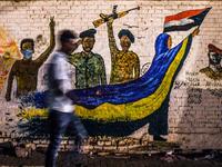 A Sudanese protester walks past a recently painted mural during a demonstration near the army headquarters in the capital Khartoum (AFP)