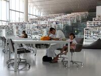 A youth works while seated at a table with a toddler inside the Qatar National Library in the capital Doha.  KARIM JAAFAR / AFP