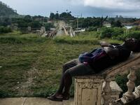 Willy, inhabitant of the roca Agostinho Neto, an abandoned cocoa plantation of Sao Tome and Principe, sleeps in front of the abandoned hospital of the roca, on May 12, 2019.  Alexis HUGUET / AFP