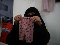 Hasna Dbeis, a 30-year-old former detainee in a Syrian-regime jail, shows baby trousers that she has sewn at a workshop employing former female detainees, in the town of Maarat Nasrin, in the rebel-held part of the Syrian Idlib province  Aaref WATAD / AFP