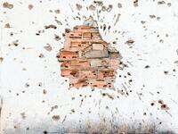 This picture shows a detail of a bullet-riddled brick wall, damaged during the Angolan civil war, in Kuito, Bie Province in Angola.  RODGER BOSCH / AFP