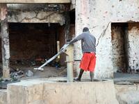 A man uses a hand pump to wash his feet outside a building damaged by bullet holes, dating from the Angolan civil war RODGER BOSCH / AFP