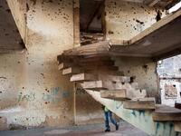 A person walks past a staircase in the bullet-riddled and graffiti-covered shell of a building that used to house Jonas Savimbi, leader of the rebel UNITA movement  RODGER BOSCH / AFP