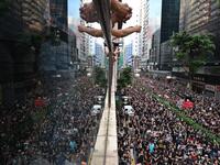  Thousands of protesters (R) dressed in black as reflected on the glass over a balcony (L) as they take part in a new rally against a controversial extradition law proposal in Hong Kong.  HECTOR RETAMAL / AFP