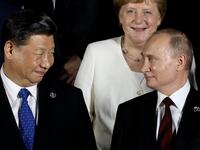 German Chancellor Angela Merkel stands behind Russian President Vladimir Putin (front R) and Chinese President Xi Jinping as they arrive to pose for a group photo before a cultural event at the Osaka Geihinkan in Osaka Castle Park during the G20 Summit in Osaka on June 28, 2019.  Dominique JACOVIDES / POOL / AFP
