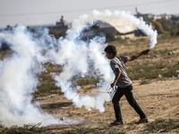 A Palestinian protester carries a tear gas canister to be thrown back at Israeli forces across the border during protests along the border with Israel east of Khan Yunis in the southern Gaza strip on July 5, 2019.  SAID KHATIB / AFP
