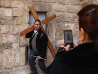 A Coptic Orthodox pilgrim poses for a picture as he carries a wooden cross at the church of the Holy Sepulchre in Jerusalem's Old City, on April 25, 2019 during the Orthodox Holy Week.  GALI TIBBON / AFP