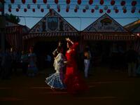 Women in traditional Sevillian dresses dance during the "Feria de Abril" (April Fair) festival in Seville on May 6, 2019. The fair dates back to 1847 when it was originally organized as a livestock fair but has turned into a week of flamenco dancing, music and bullfighting.  CRISTINA QUICLER / AFP