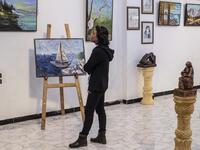 Amal al-Attar, a 37-year-old artist, looks at her artworks on display during an exhibition at the first cultural centre to open since ISIS rule ended in the eastern Syrian city of Raqa on May 1, 2019. DELIL SOULEIMAN / AFP