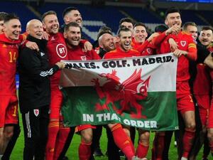 بايل وزملاؤه في منتخب ويلز يرفعون العلم وعليه كلمات: ويلز، الغولف، مدريد