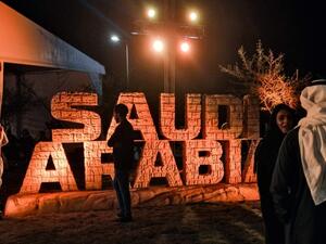 People stand before a sign showing the logo of the Dakar Saudi Arabia 2020 rally, during a press conference about the event in Qiddiya.
