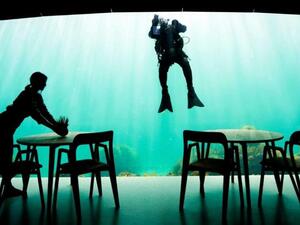 A worker prepares dining tables as a diver cleans a viewing window of Under, a restaurant that is semi-submerged beneath the water of the North Sea in Lindesnes, some 400 km southwest of Oslo, Norway. (AFP)