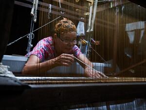 This photo taken on May 22, 2019 shows Rampai Sripetch, a 65-year-old Thai Muslim woman, weaving silk fabric on a loom at a workshop near Darul Falah mosque in Bangkok. (Romeo GACAD / AFP)