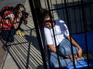 A photographer takes a picture of a teenager sitting in a cage during a protest of international labor groups, civil society and students against the policy of migrant family separation along the US-Mexico border on June 17, 2019 in front of the United Nations offices in Geneva. (FABRICE COFFRINI / AFP) A photographer takes a picture of a teenager sitting in a cage during a protest of international labor groups, civil society and students against the policy of migrant family separation along the US-Mexico border on June 17, 2019 in front of the United Nations offices in Geneva. (FABRICE COFFRINI / AFP)