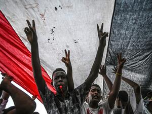 Sudanese protesters shout slogans and flash victory signs during a rally outside the army complex in Sudan's capital Khartoum. (AFP/ File Photo)