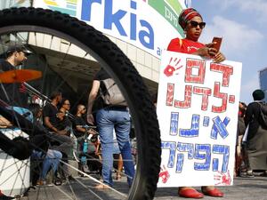 A woman holds a banner reading in Hebrew "our children blood is not lawlessness" as Israelis of Ethiopian origin protest on July 8, 2019 in Tel Aviv after the death of a young man of Ethiopian origin who was killed by an off duty police officer in Kiryat Haim. (AFP/ File Photo)