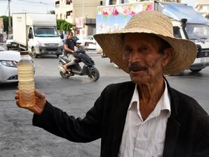 A street vendor holds a bottle of legmi, a coveted date palm drink, in the southwestern Tunisian town of Gabes on July 18, 2019. (AFP/ File Photo)