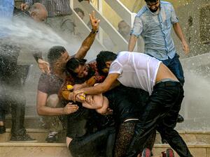 Demonstrators protect each other as they are hit by water cannon during a protest against the replacement of Kurdish mayors with state officials in three cities, in Diyarbakir, in eastern Turkey (AFP)