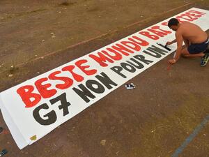 A man paints a banner reading in Basque and French "G7, no for another world" at a campsite in Urrugne on August 22, 2019 ahead of a Group of Seven (G7) summit to be held in nearby Biarritz. (AFP)