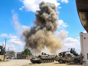 smoke plume rising from an air strike behind a tank and technicals (pickup trucks mounted with turrets) belonging to forces loyal to Libya's Government of National Accord (GNA). (AFP/ File Photo)